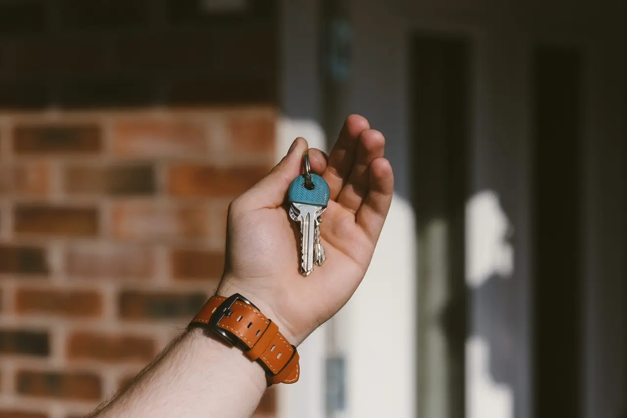 someone holding a key in front of a front door
